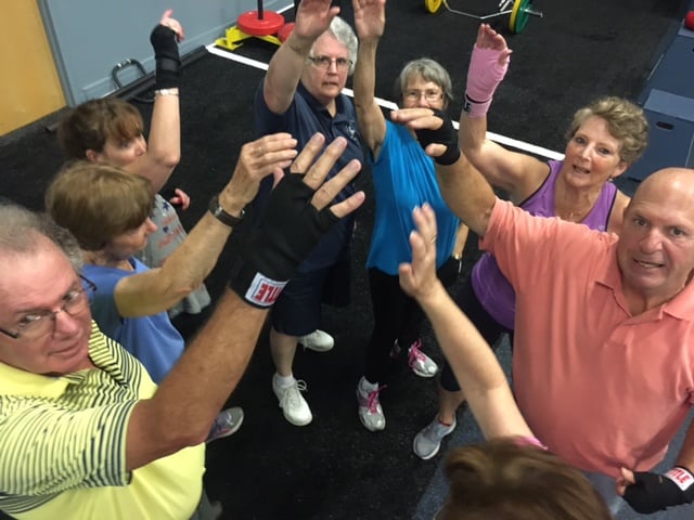 Members of a Rock Steady Boxing Group put their hands in the center for a cheer