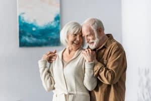 cheerful senior man touching shoulders of happy wife