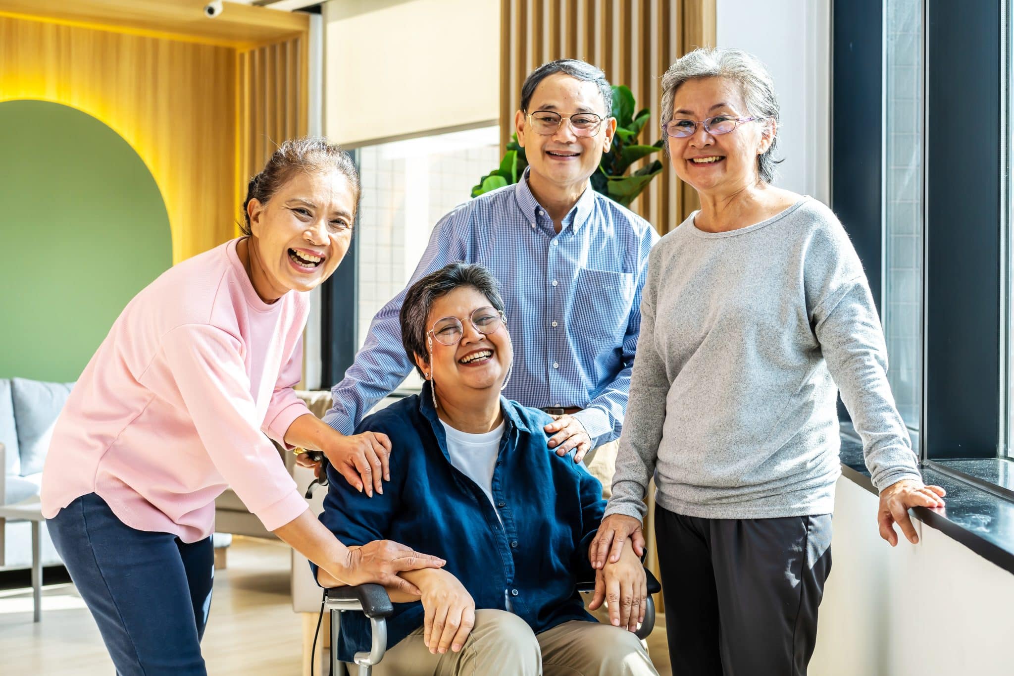 Group of asia happy retired senior people enjoy standing relax at hospital, portrait of asian senior male female friend group sit of wheelchair smiling together and look at camera